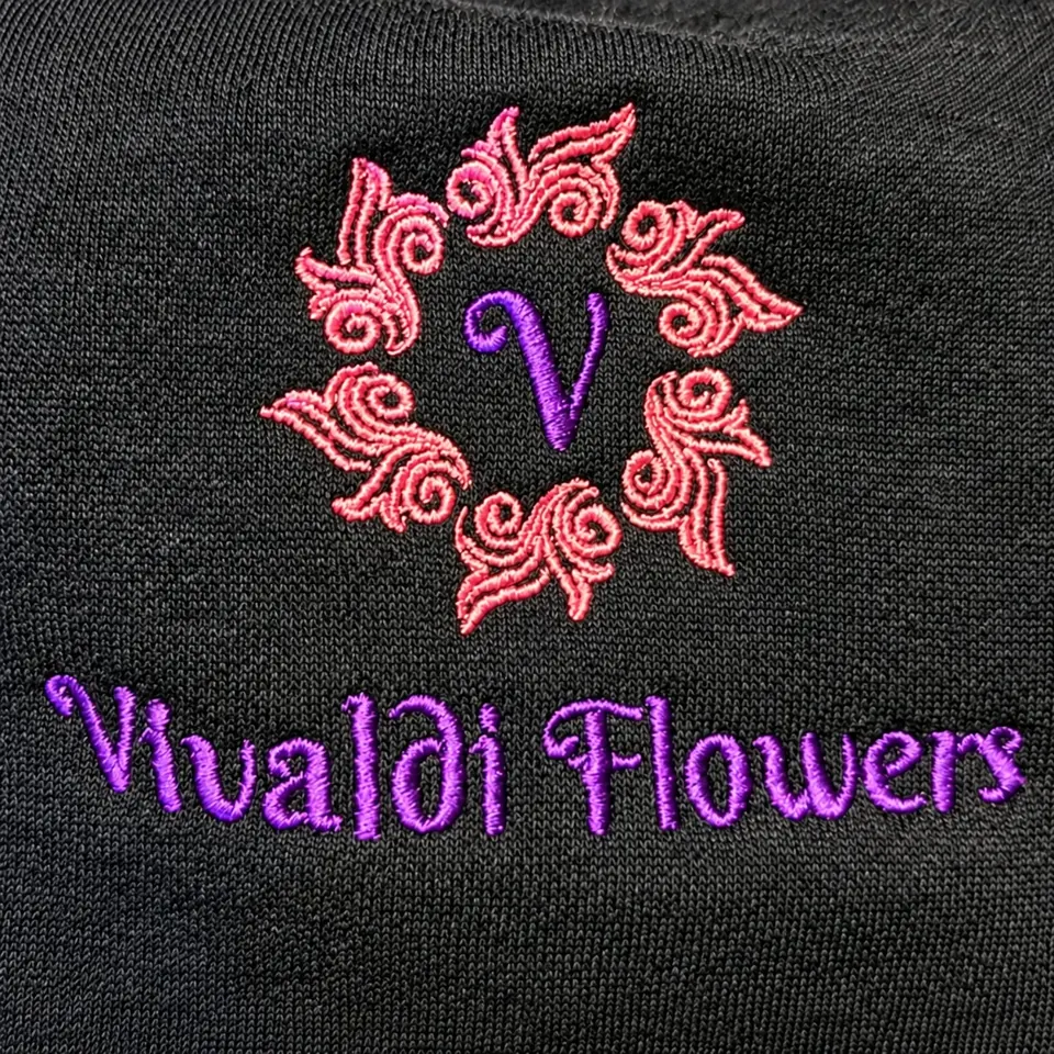 Vivaldi Flowers logo with a pink embroidered wreath on dark fabric